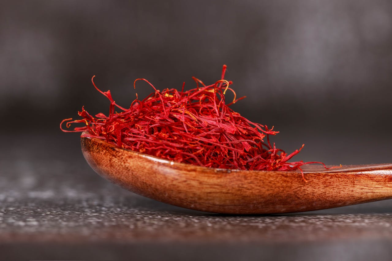 Detailed close-up of vibrant saffron threads in a wooden spoon, perfect for culinary imagery.